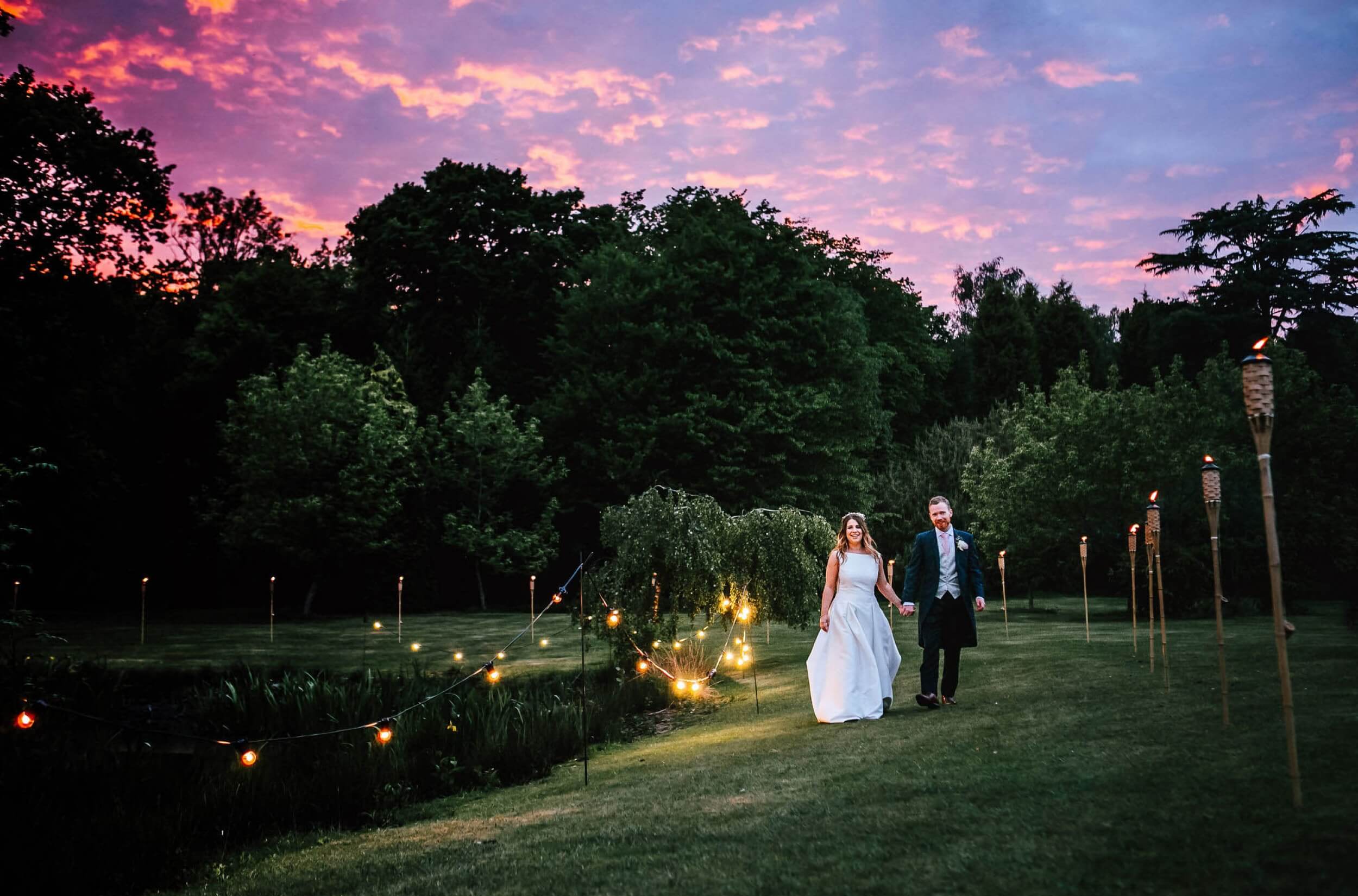 Wedded couple walking along the water in a field