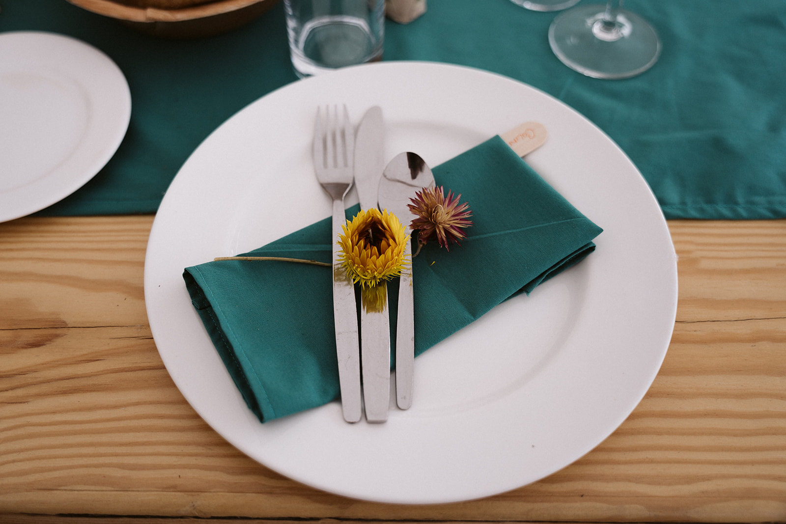 place setting with a green napkin and wildflower