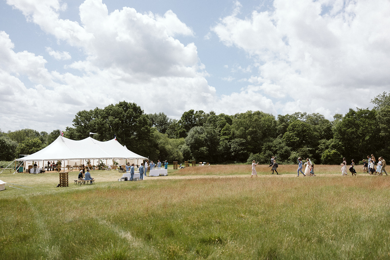people walking to a sailcloth marquee in a field