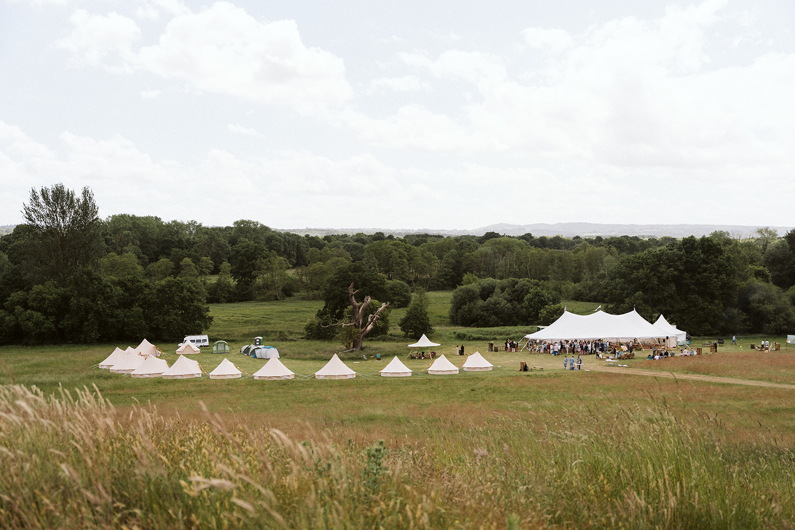 sailcloth marquee in a field with bell tents