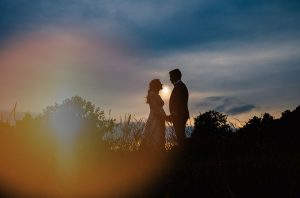 Wedded couple standing in silhouette at magic hour